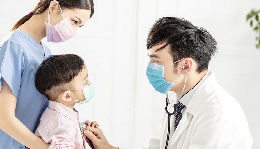 medical doctor wear mask and examining little boy in clinic